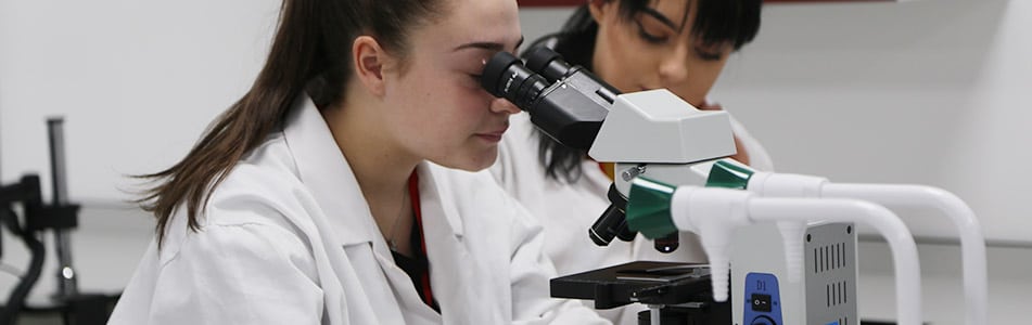 Science student looking in microscope